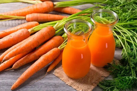 Two flasks of carrot juice along with whole carrots