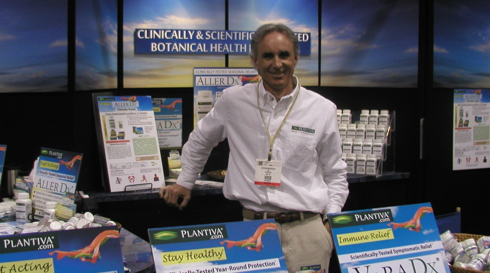 A man stands at a trade show booth with the Plantiva logo