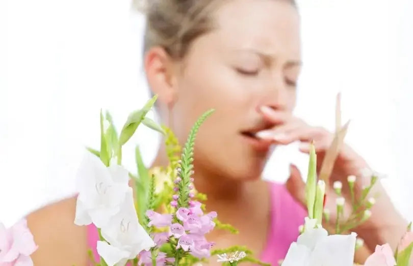 A woman sneezing with a bouquet of flowers