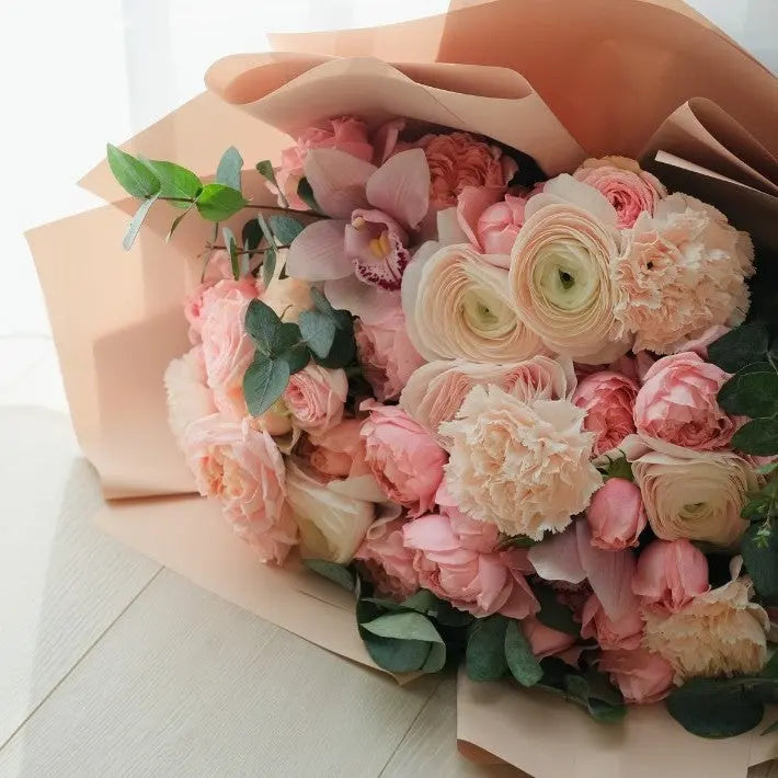 A bouquet of pink and white flowers wrapped in pink paper