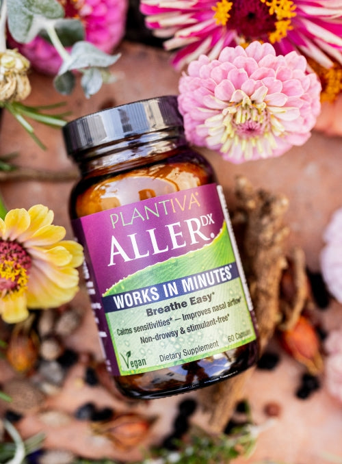 A bottle of AllerDx with flowers and other botanicals