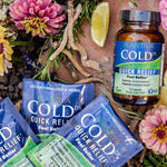 Cold DX quick relief supplement packets and bottle surrounded by flowers and herbs.