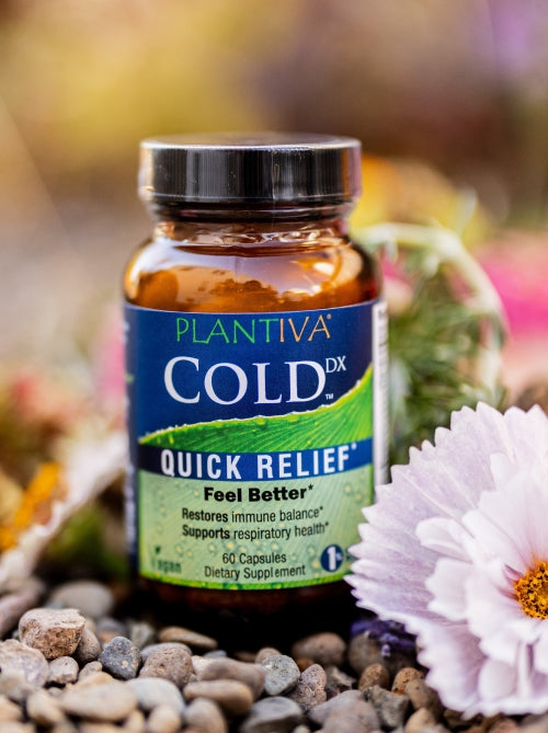 A bottle of ColdDx with flowers and other botanicals