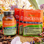 One bottle and three packets of Digestiv with flowers and other botanicals in the background