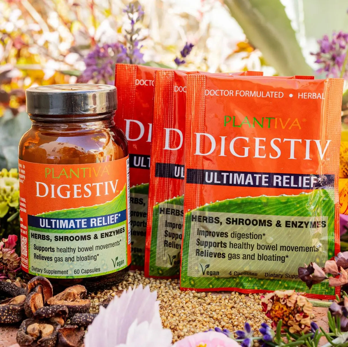 One bottle and three packets of Digestiv with flowers and other botanicals in the background