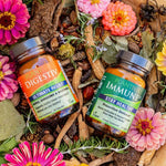 A bottle of Digestiv and a bottle of ImmuneDx with flowers and other botanicals