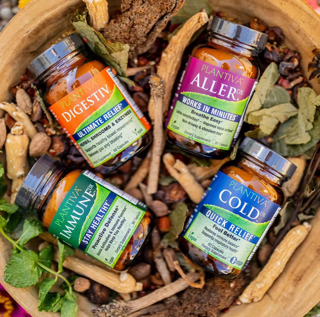 Bottles of Digestiv, AllerDx, ImmuneDx and ColdDx in a wooden bowl with leaves and other botanicals