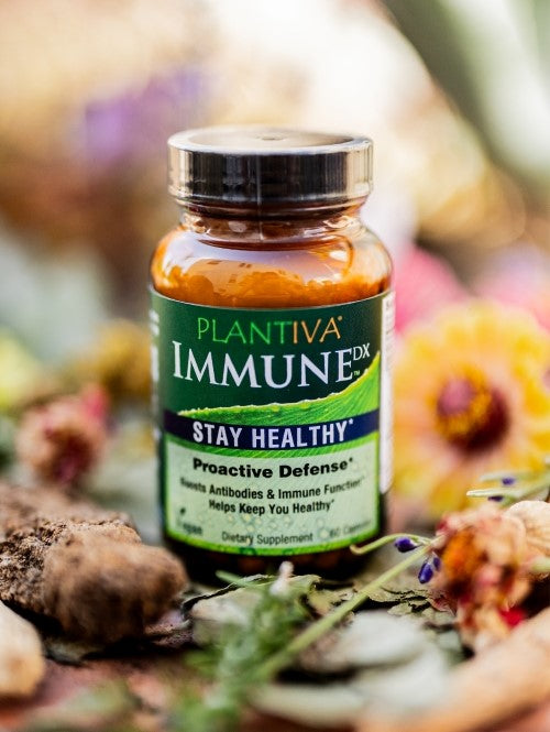 A bottle of ImmuneDx with flowers and other botanicals