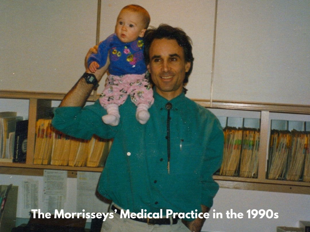 Man holding a baby in a medical office setting with text overlay about 'The Morrisseys' Medical Practice in the 1990s'.