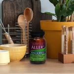 Plantiva AllerDX supplement bottle on a wooden counter with kitchen items in the background